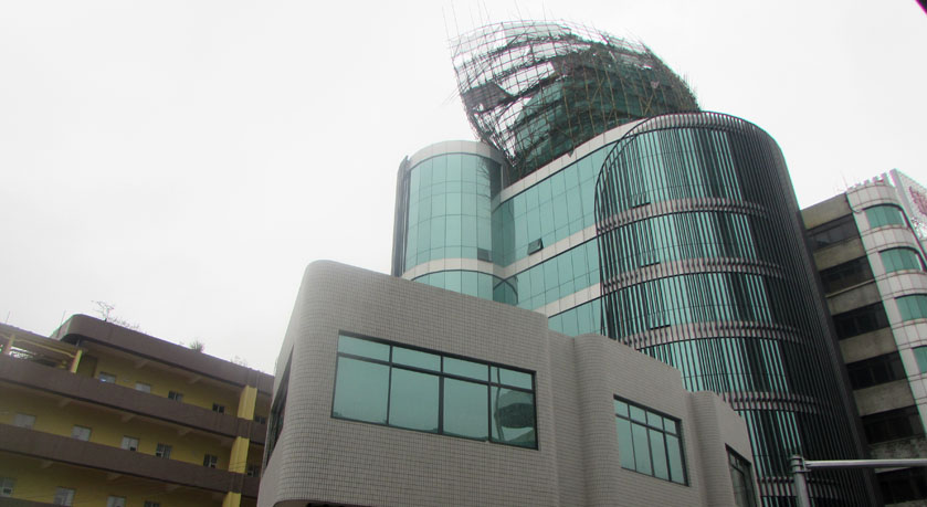 飛馬路口如家酒店旁一建筑樓頂正在裝修，北風吹后，不得不拆除
