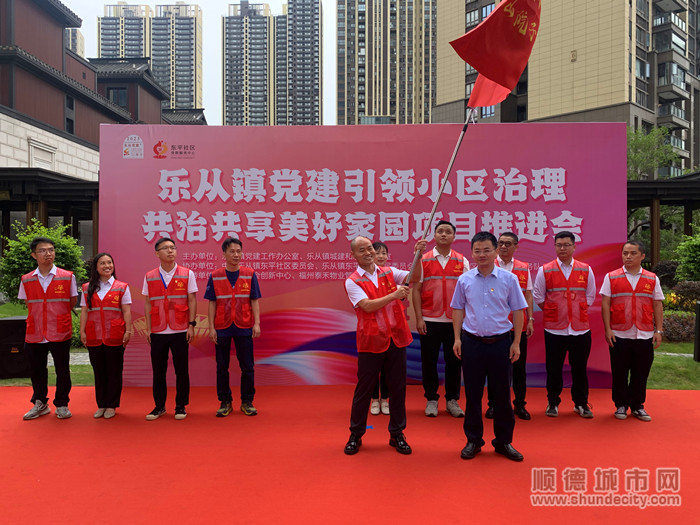 樂從鎮黨委副書記陳子榮（右）對樂從鎮首個小區共治共享黨群先鋒隊進行授旗。.jpg