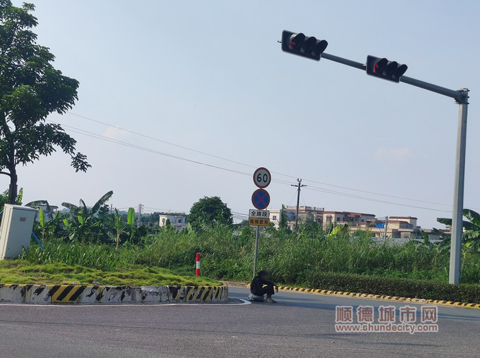 一名流浪老人難頂烈日曝曬，正蹲坐在均安新均欖路新華段公路十字路口花基旁。（均安鎮公共服務辦公室供圖）_副本.jpg